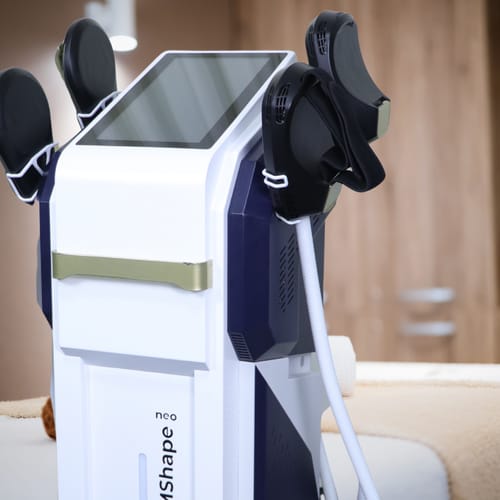 Close-up view of a body contouring machine with multiple applicators for fat reduction and muscle toning, featuring a screen interface.